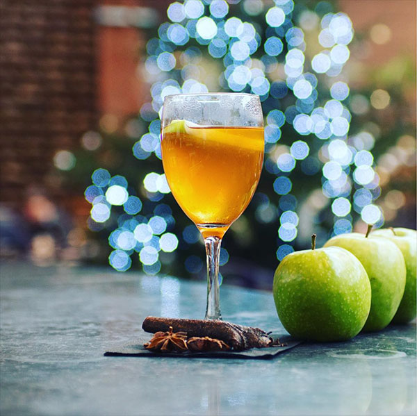 Festive cocktail with a beautifully lit Christmas tree in theforeground.